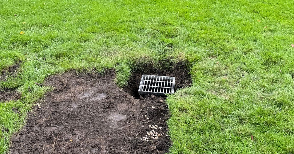 Channel drain and underground 4-inch PVC drainage system installed at a residential driveway in Elmhurst, IL to capture surface runoff and reduce water pooling.