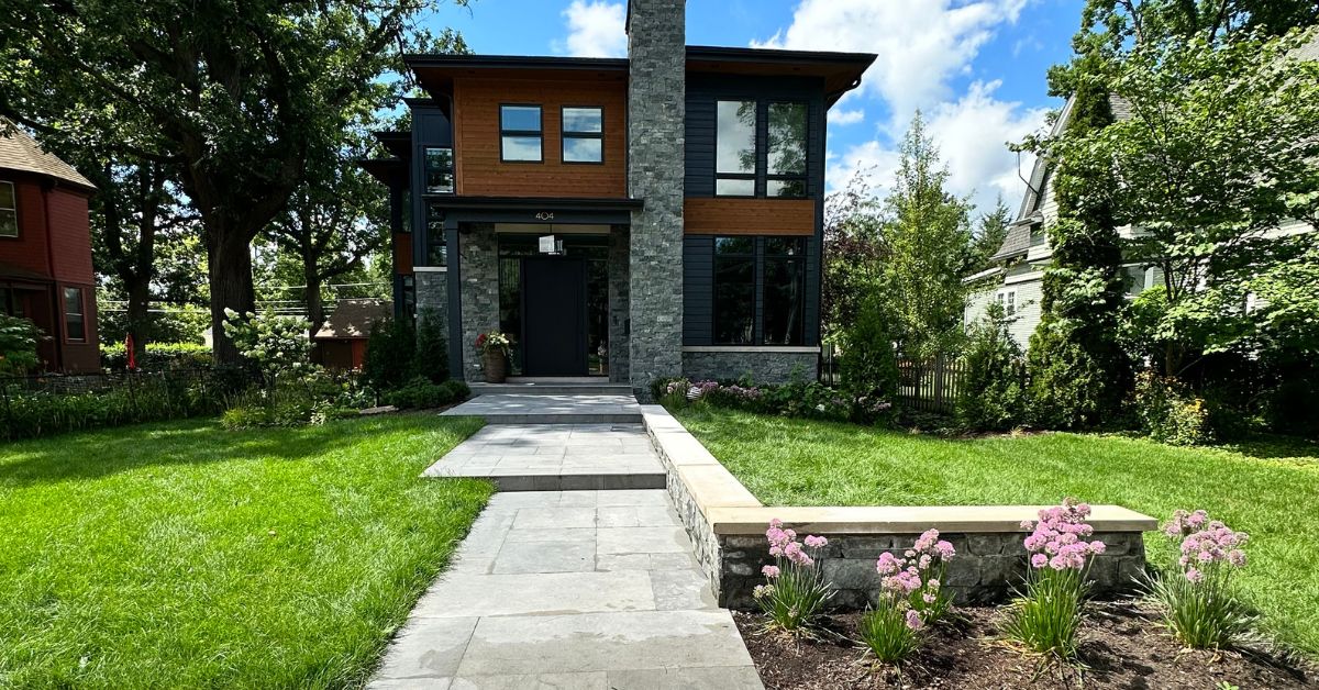 Park Ridge, IL landscape project featuring new plantings, concrete patios and walkways, porcelain tile, stonework, drainage, landscape lighting, and custom ornamental steel fencing.
