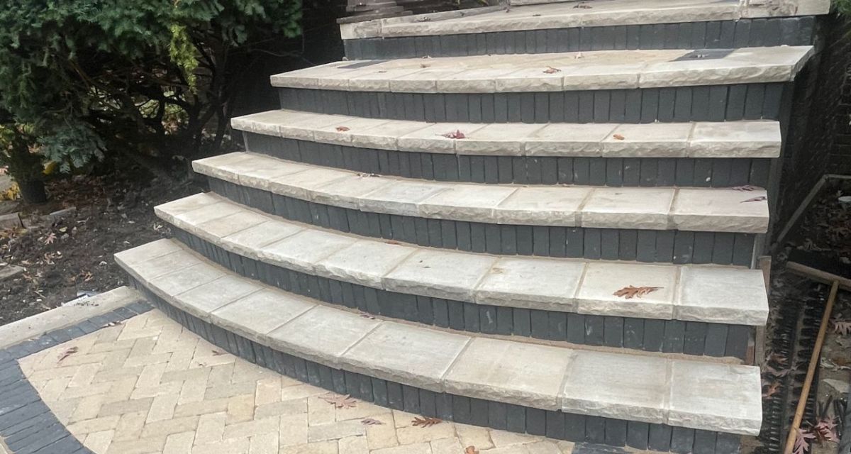 Park Ridge front staircase and Unilock walkway with limestone treads, curved concrete steps, and integrated NDS drainage system