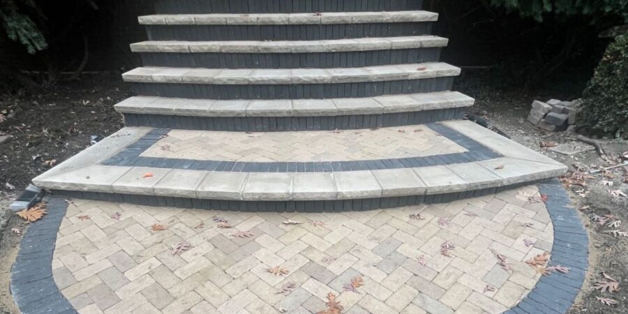 Park Ridge front staircase and Unilock walkway with limestone treads, curved concrete steps, and integrated NDS drainage system