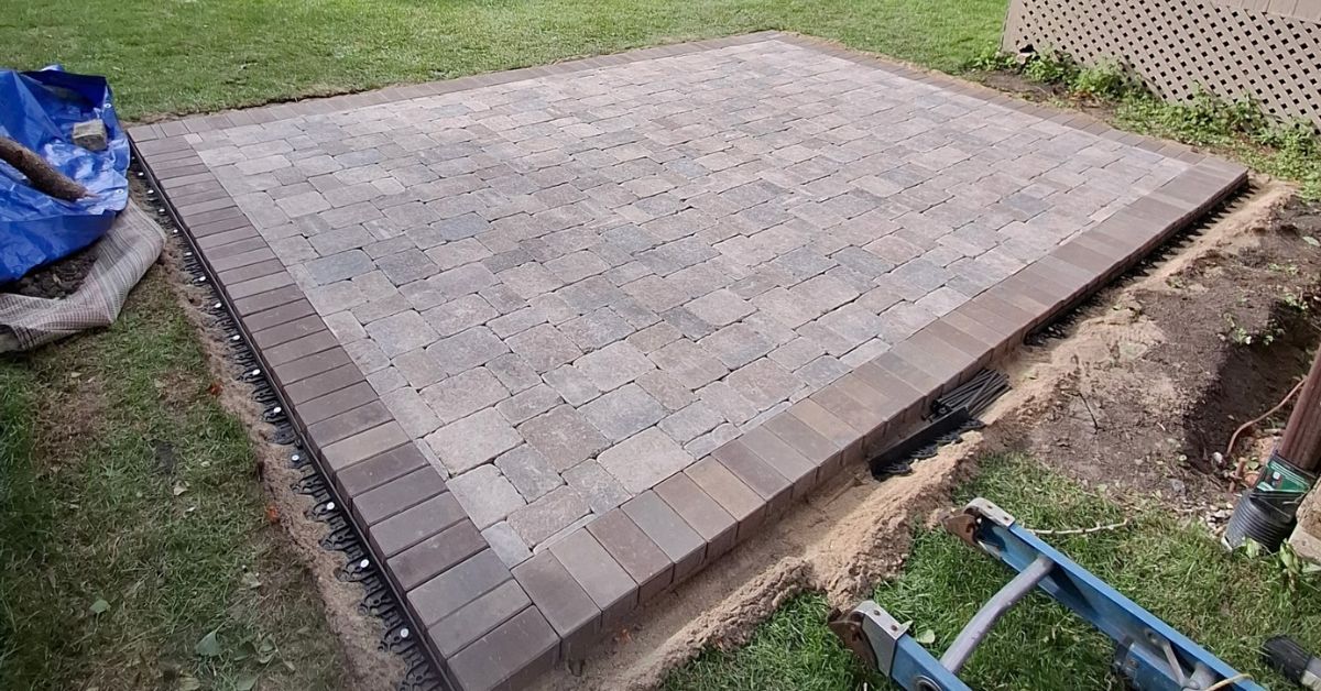 Custom Unilock Brussels Block patio installation in Northbrook, IL with a Hollandstone border, polymeric joint sand, and natural bluestone stepping stones.