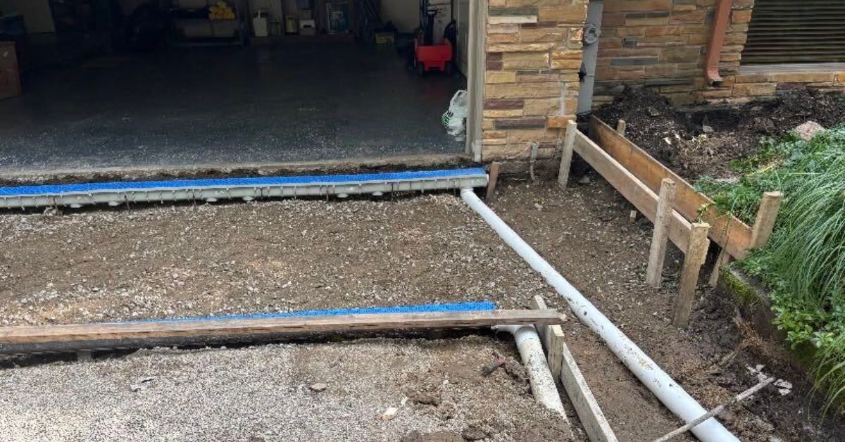 Riverwoods NDS drainage upgrade with new driveway, channel drains and rebuilt lines preventing garage and yard floods.
