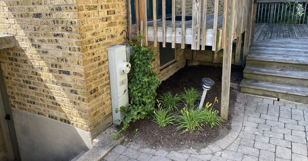 Rebuilt stone retaining wall and landscape installation in Lincolnwood, IL featuring drainage improvements, hydrangeas, boxwoods, ornamental grasses, and perennial plantings.