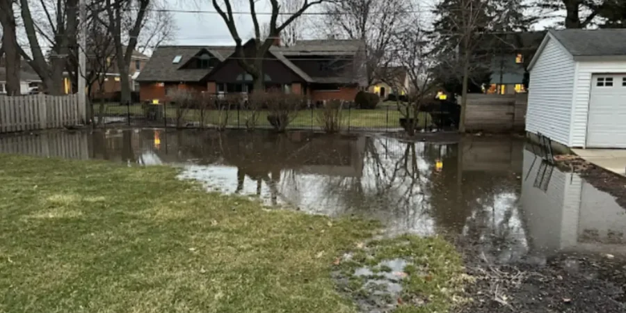 Backyard flooding covering residential lawn after early spring rainstorm.