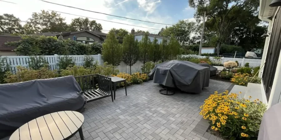 Modern backyard in Glencoe with stone paver patio, native flowers, outdoor seating, and covered grill station.