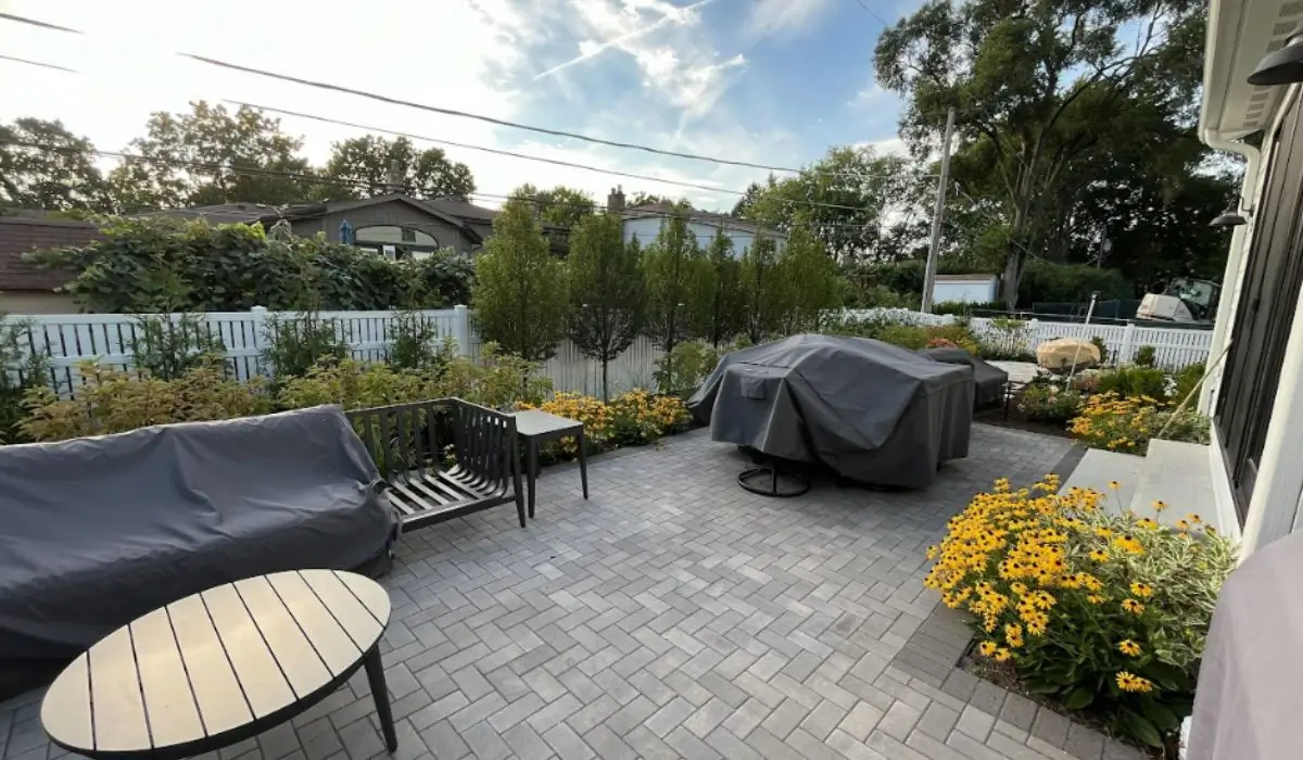Modern backyard in Glencoe with stone paver patio, native flowers, outdoor seating, and covered grill station.
