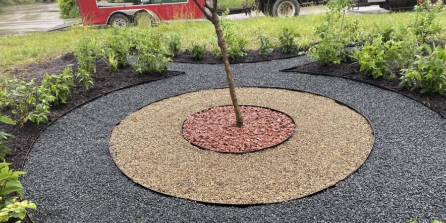 Niles backyard featuring a custom rain garden with Stone Taurus symbol, native pollinator plants, blueberries, hydrangeas, granite, and steel edging for sustainable landscaping.