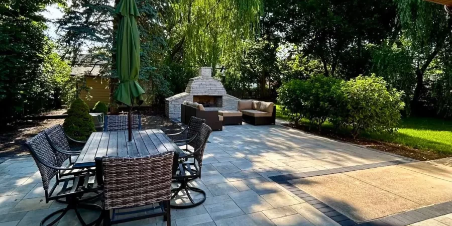 Outdoor kitchen with Built-In Fire Features including a stone fireplace, patio seating, and dining area in Glencoe.