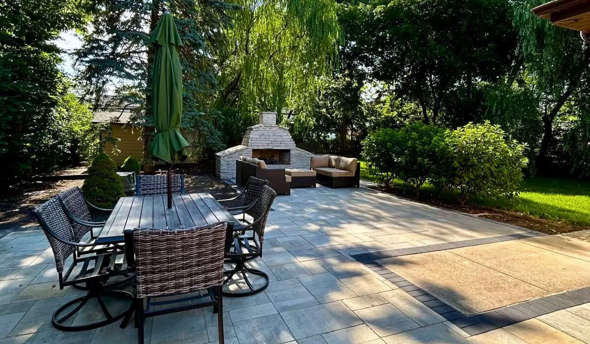 Outdoor kitchen with Built-In Fire Features including a stone fireplace, patio seating, and dining area in Glencoe.