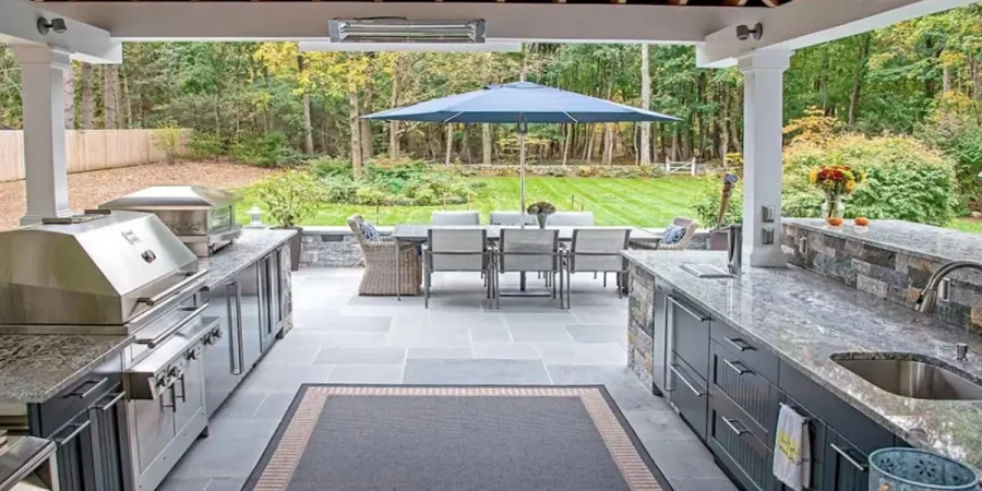 Outdoor kitchen in Glencoe featuring a wood-fired pizza oven and modern grill with outdoor dining setup.