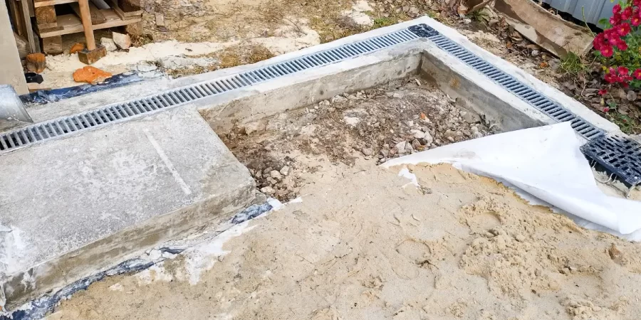 Drainage solutions with surface trench grate system to redirect water and prevent foundation oversaturation and erosion.