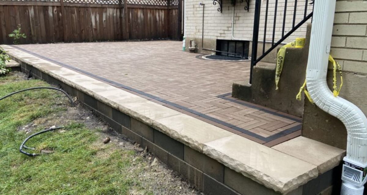 Wilmette hardscape renovation featuring Unilock pavers, rebuilt front stoop, custom iron railings, and buried drainage lines.