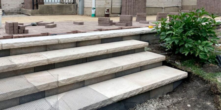 Wilmette hardscape renovation featuring Unilock pavers, rebuilt front stoop, custom iron railings, and buried drainage lines.