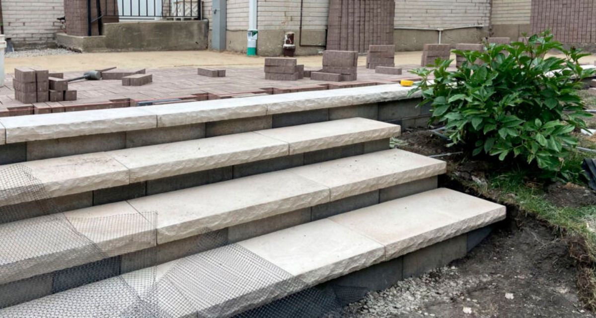 Wilmette hardscape renovation featuring Unilock pavers, rebuilt front stoop, custom iron railings, and buried drainage lines.