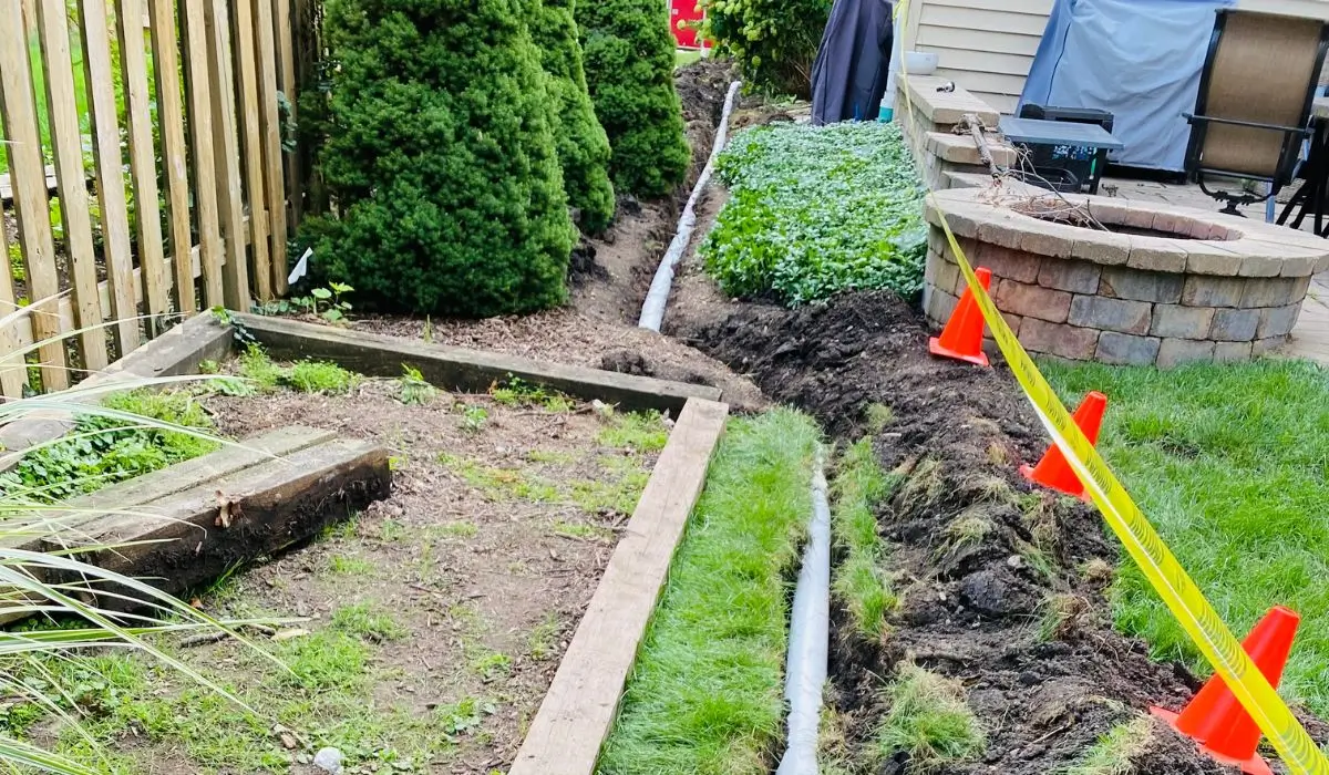 Trenches dug with pipes installed to improve yard drainage and prevent spring flooding near backyard patio.